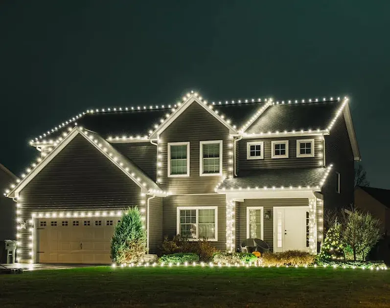 Warm white Christmas lights along the rooflines and windows of a home
